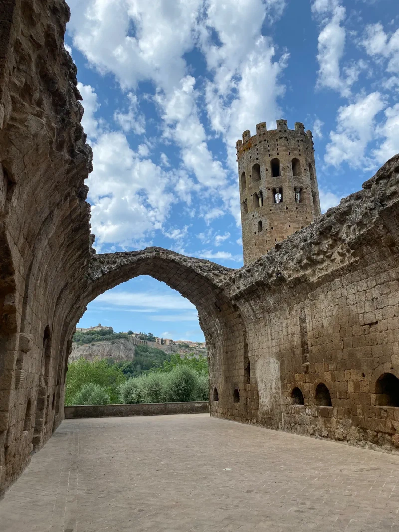 Abbey ruins with Gothic arch framing the tower and Orvieto in the distance