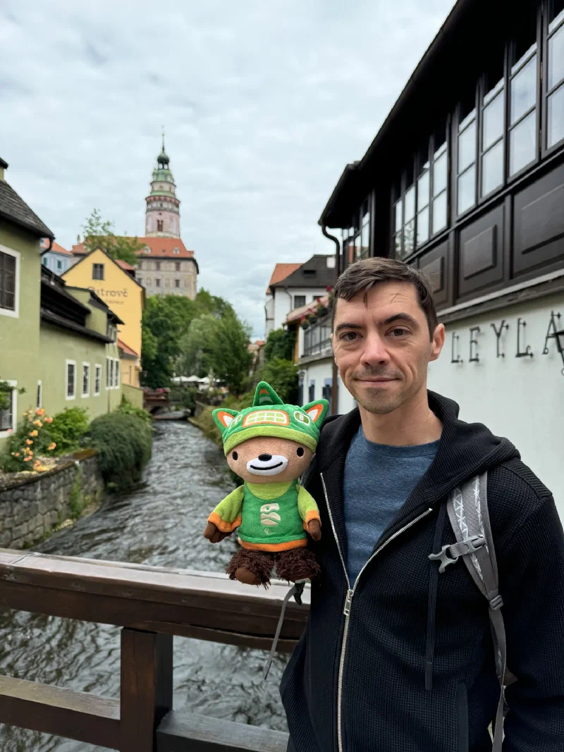Nicholas and Sumi Bear on a bridge with the castle tower behind
