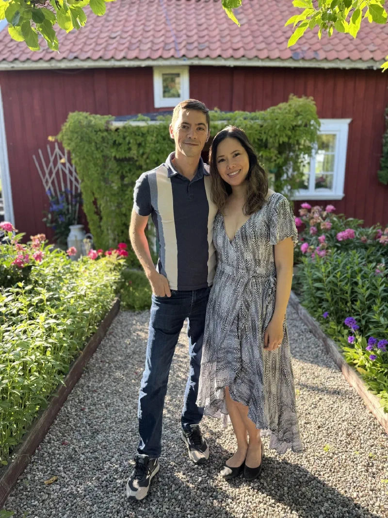 Nicholas and Pokin posing in the garden of a red Swedish house