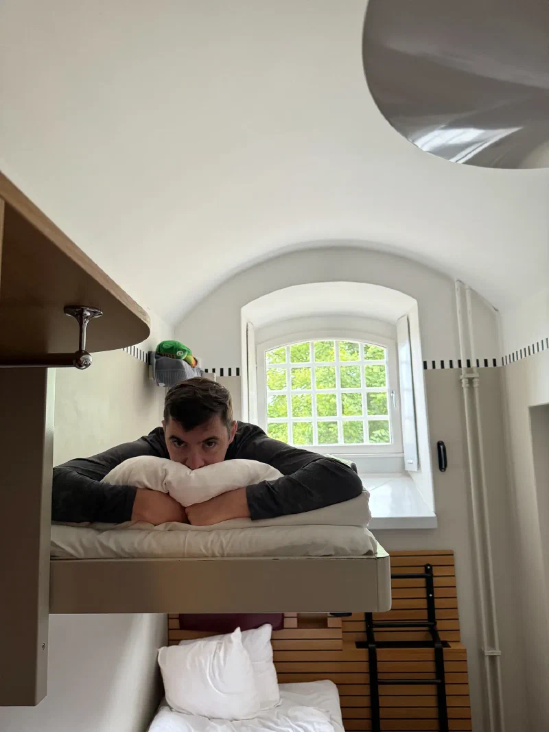 Nicholas lying on top bunk hugging a pillow, with Sumi on the shelf above