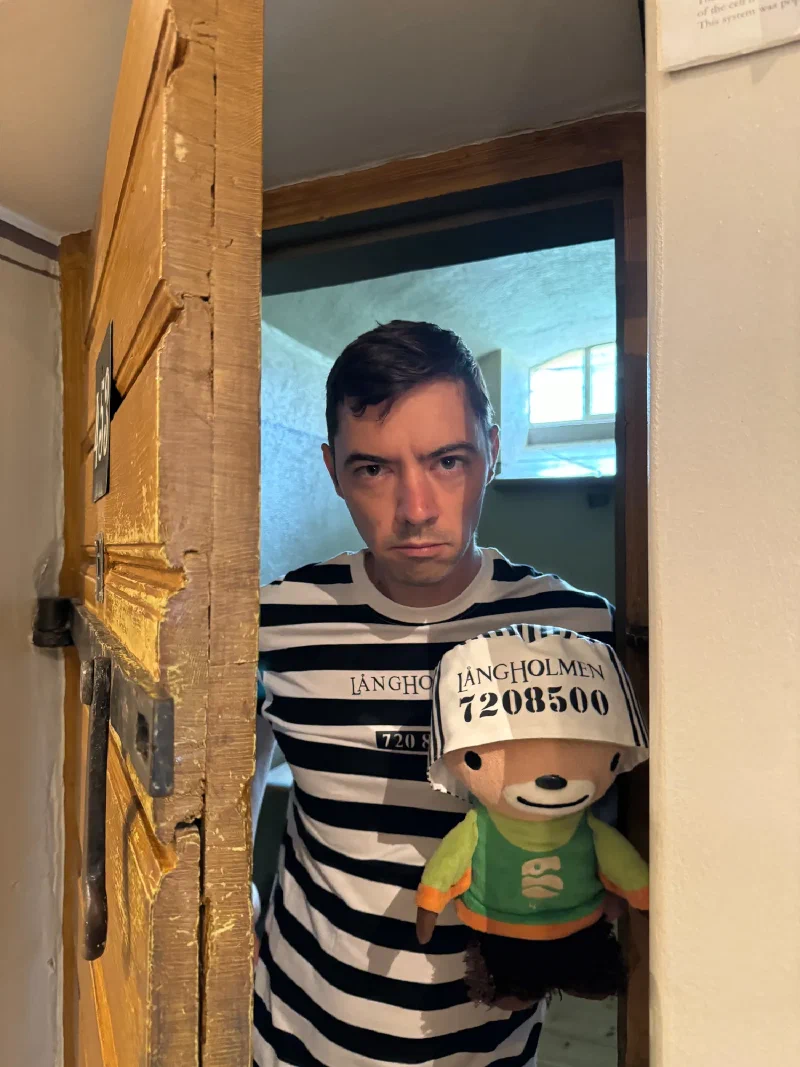 Nicholas holding Sumi while peering through a heavy wooden prison door