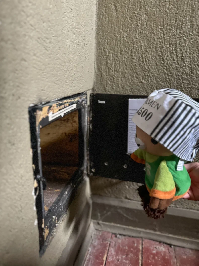 Sumi peering into a small metal hatch in the prison wall