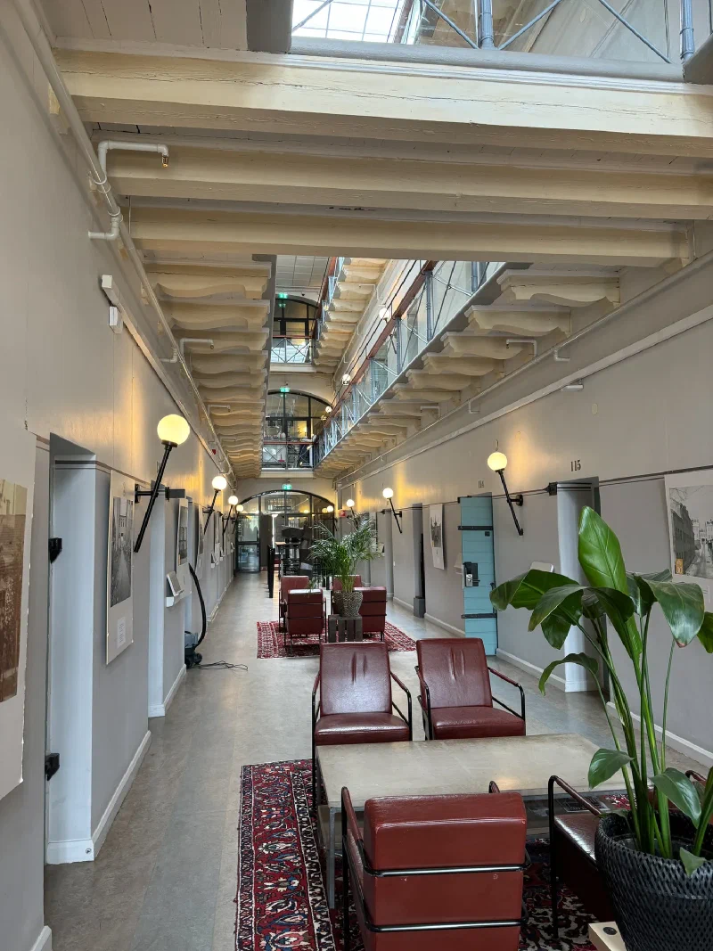 Prison corridor converted to hotel common area with skylit atrium and leather chairs