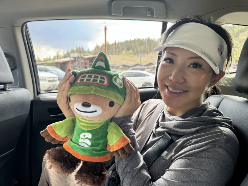 Po On holding Sumi Bear in the back of a car, cupping his ears