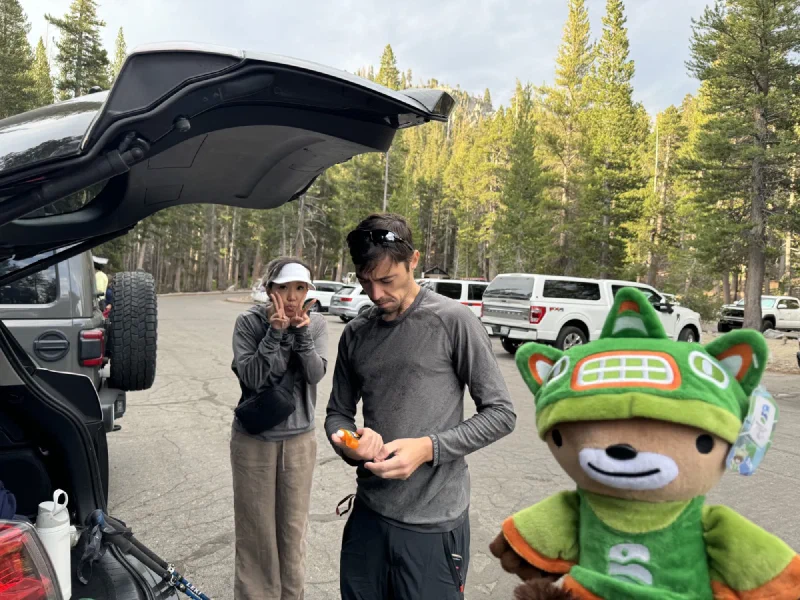 Sumi Bear photobombing the foreground while Nicholas and Po On are in the background of a parking lot