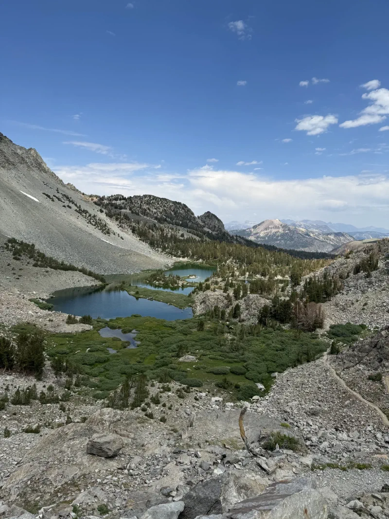 Panoramic view from a high ridge looking down at turquoise tarns and green meadows