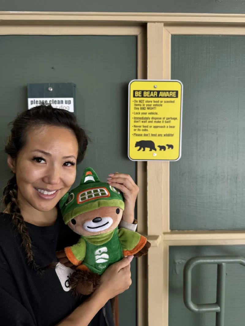 Po On holding Sumi Bear next to a yellow BE BEAR AWARE warning sign