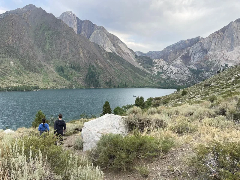 Two people looking out at a large alpine lake surrounded by mountains
