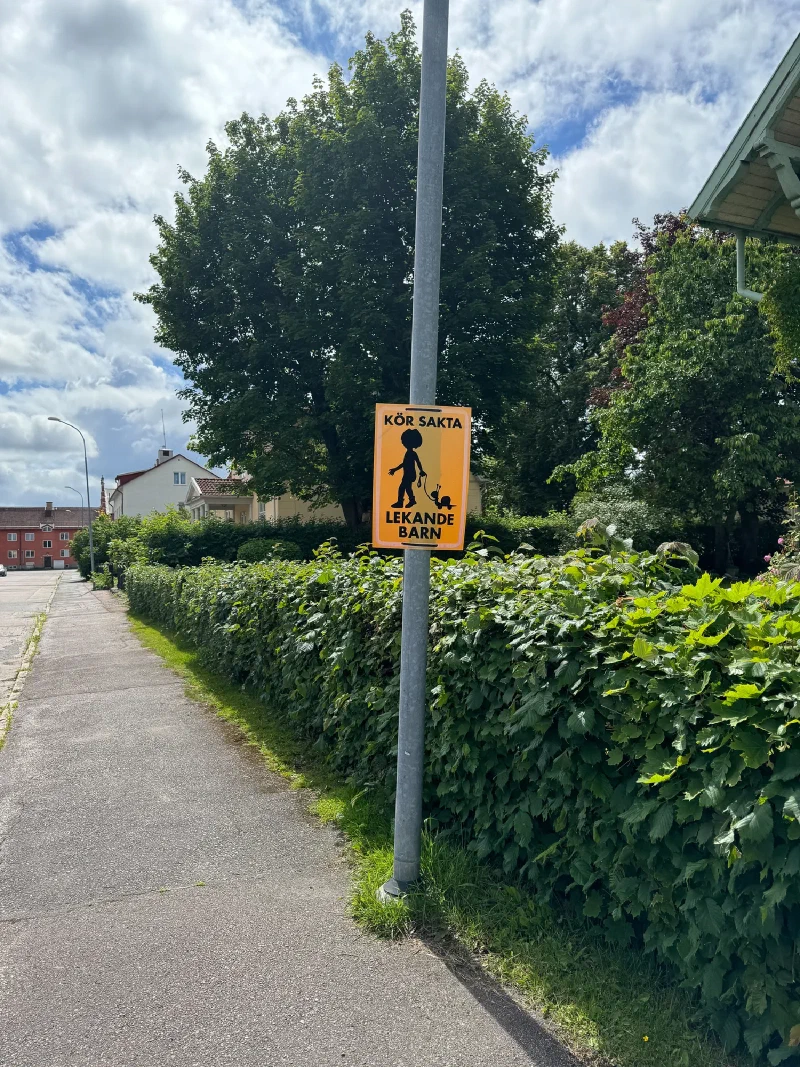 Swedish neighborhood sign reading KÖR SAKTA LEKANDE BARN