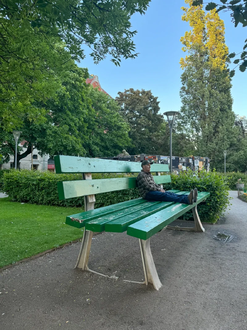 Adam sitting on an oversized green bench in Örebro park