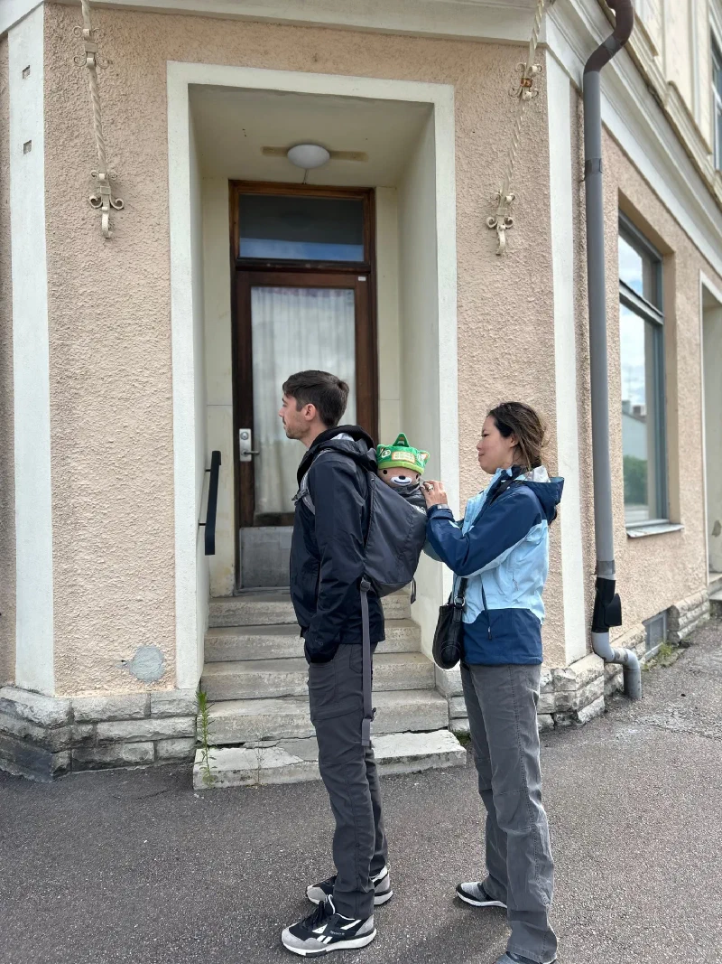 Pokin positioning Sumi in Nicholas's backpack in front of Oskar's old barbershop