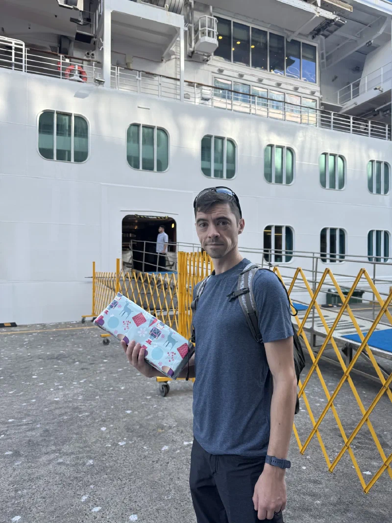 Nicholas at the port with a gift, cruise ship behind