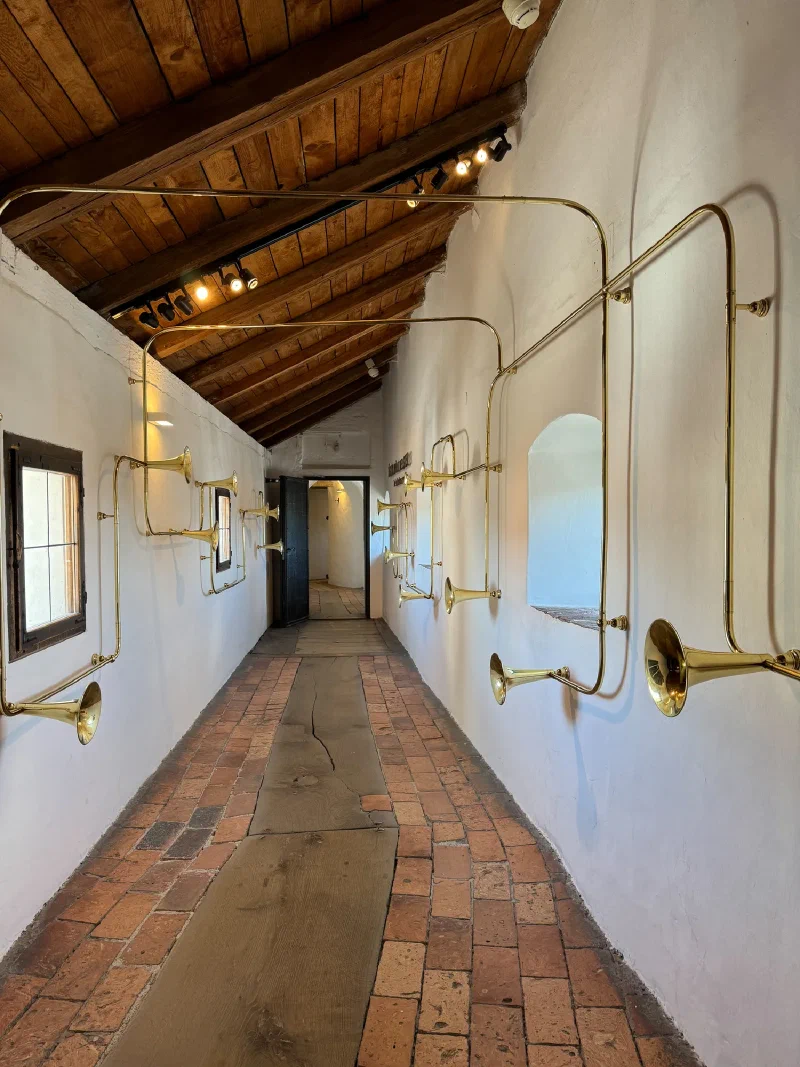 Corridor with brass horns and trumpets mounted on walls connected by piping