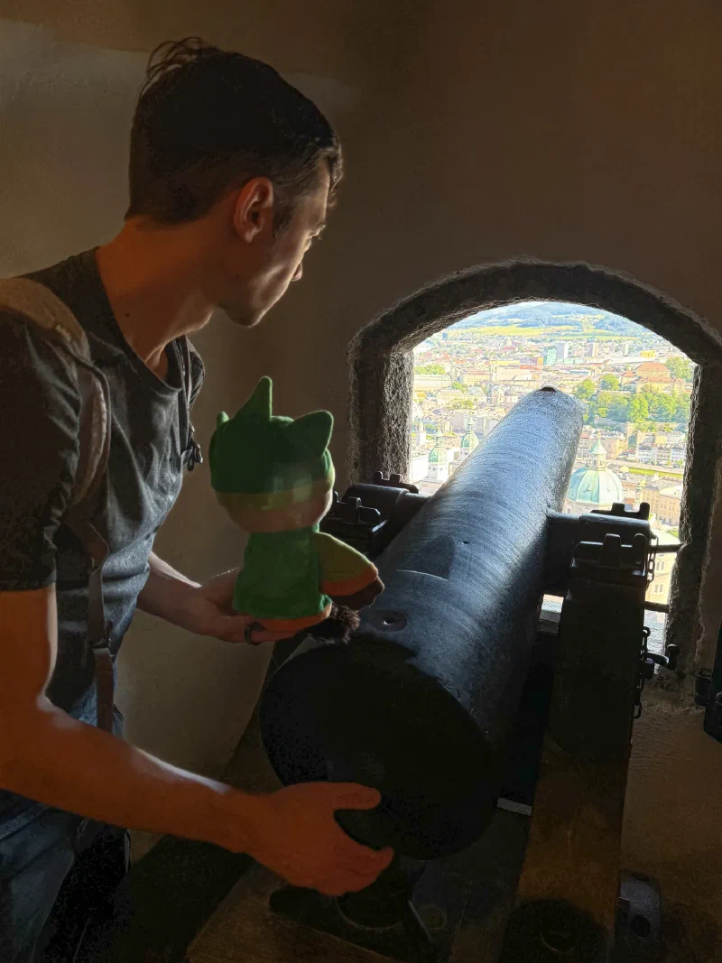 Nicholas with Sumi looking through a cannon embrasure at Hohensalzburg with cathedral visible through the window