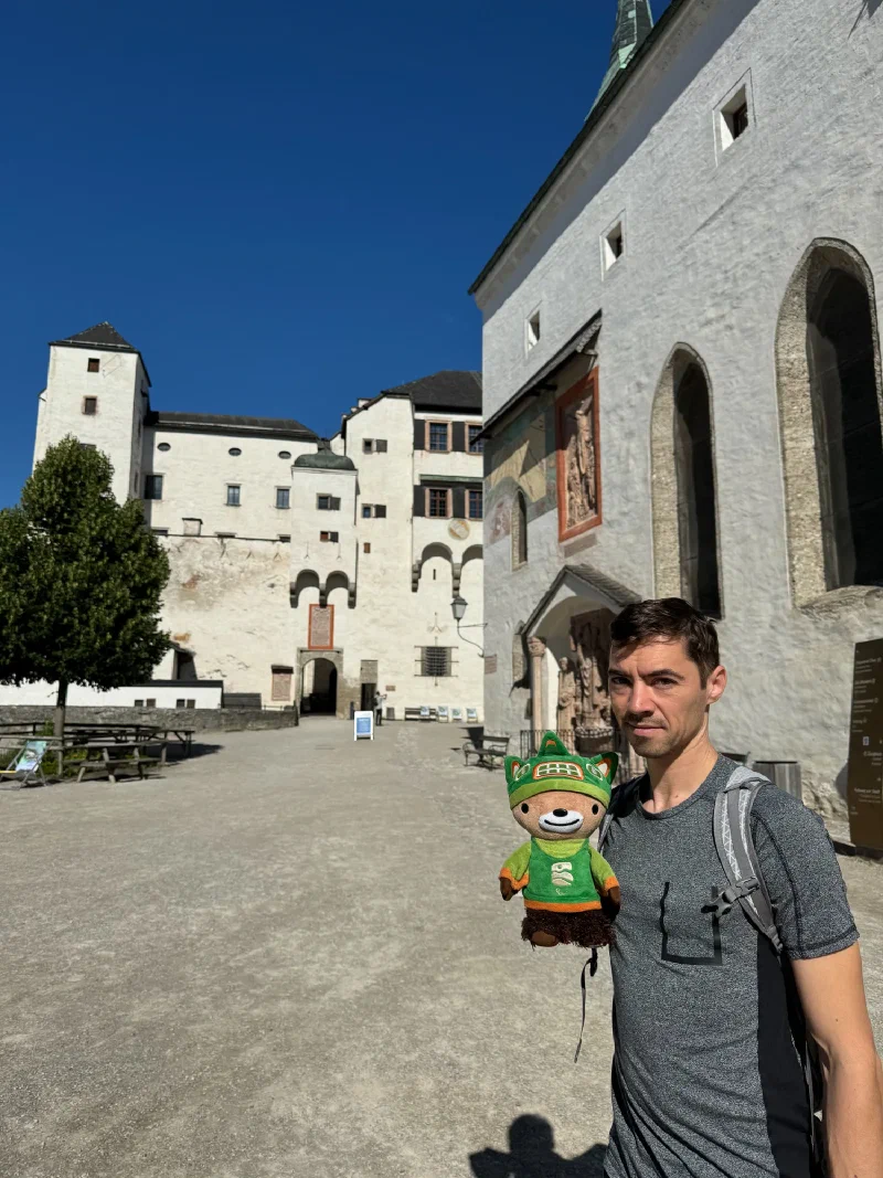 Nicholas with Sumi in the empty Hohensalzburg Fortress courtyard with white walls and blue sky