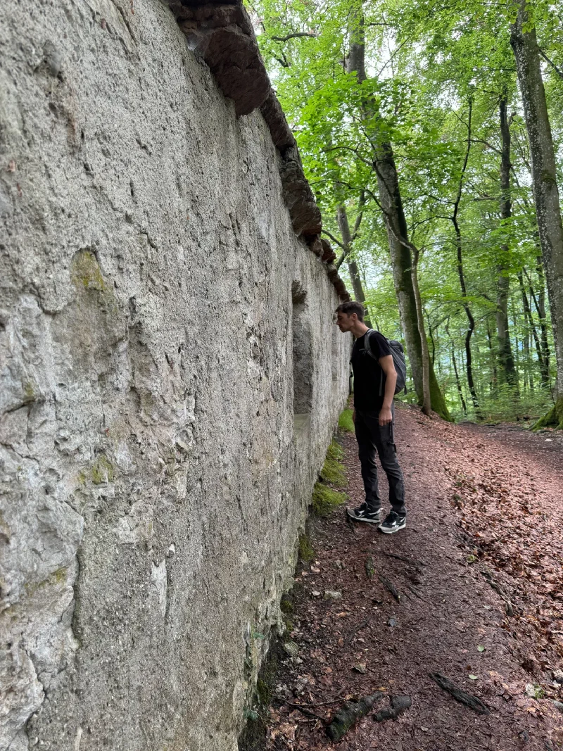 Nicholas peering into a stone ruin wall