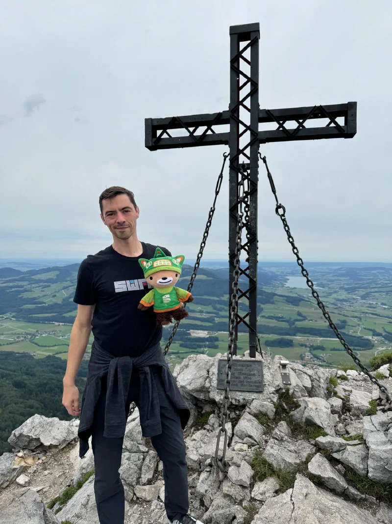 Nicholas with Sumi at the summit cross with valley and lake below