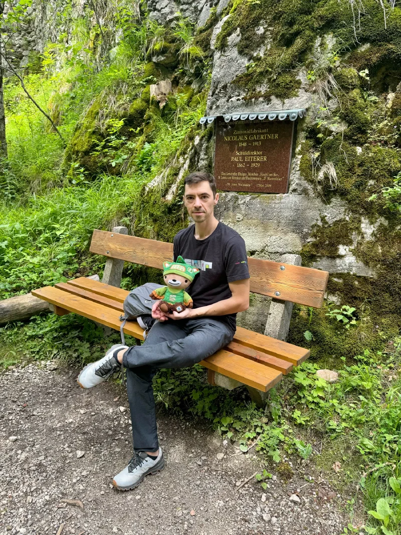 Close-up at the ruin bench showing memorial plaque in mossy rock