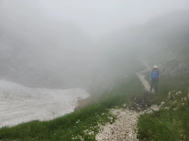 Foggy alpine trail with snow patch on Untersberg