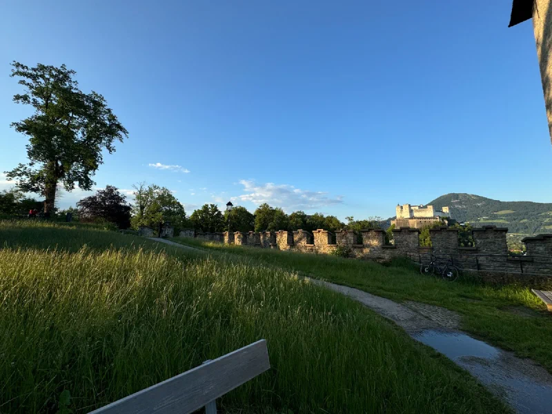 Grassy path with old wall and Hohensalzburg Fortress in the distance