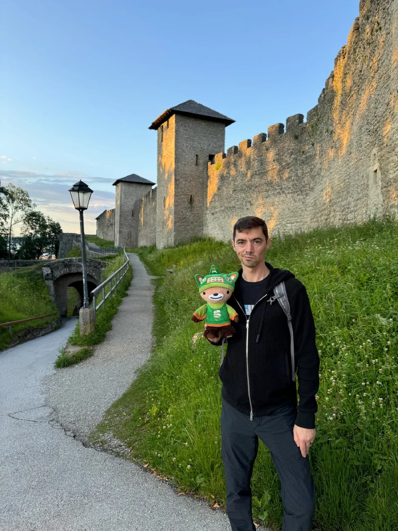Nicholas holding Sumi on the fortress path with medieval architecture behind