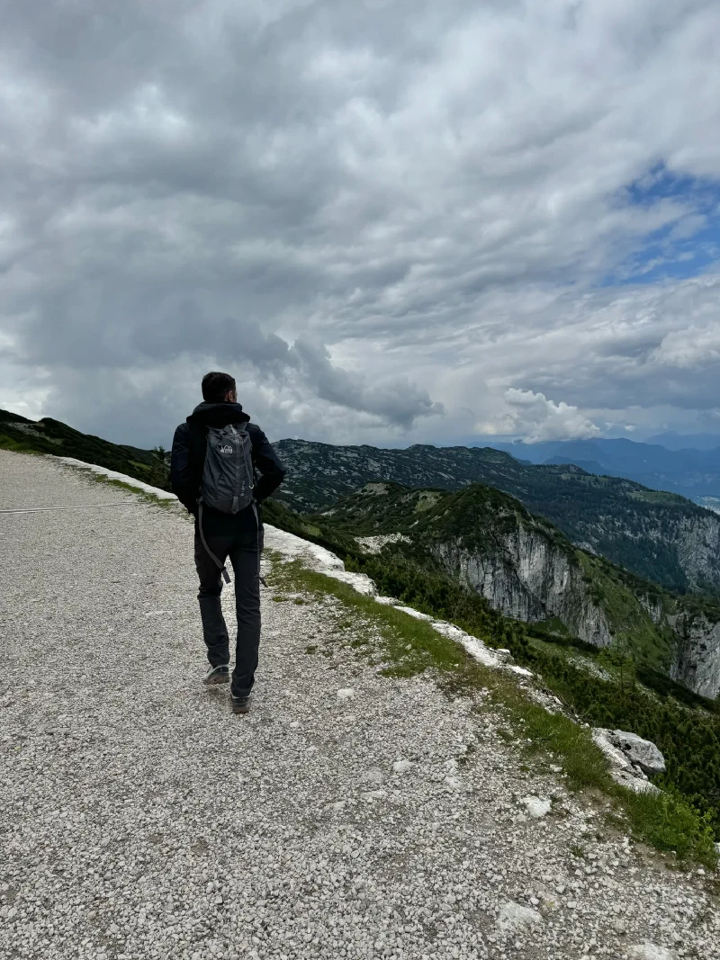 Hiker on the Untersberg ridge path under dramatic clouds