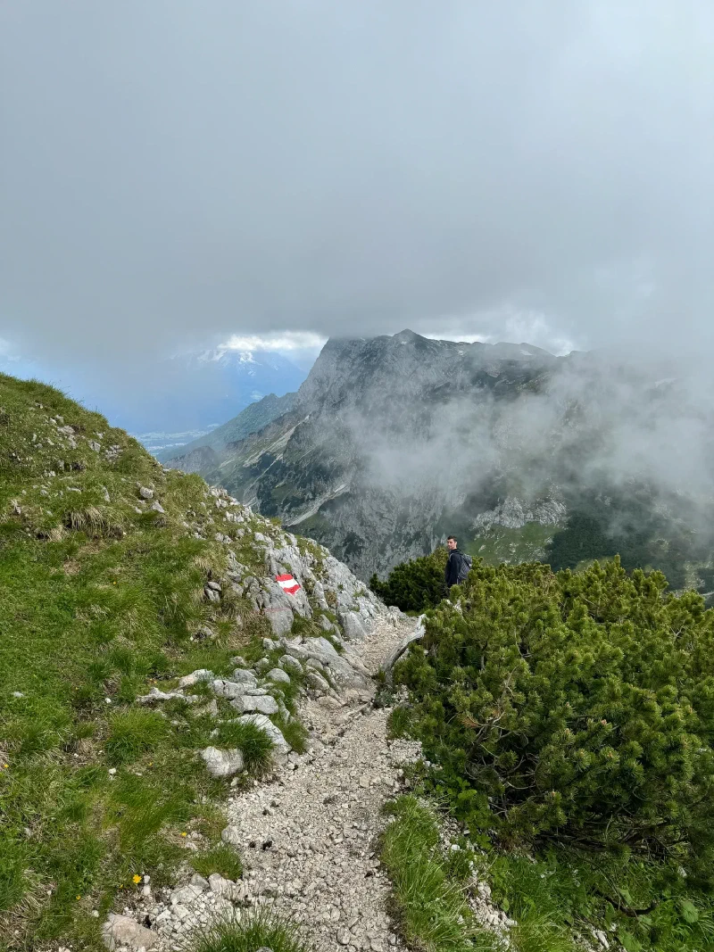 Hiker on exposed mountain trail with limestone cliffs and fog