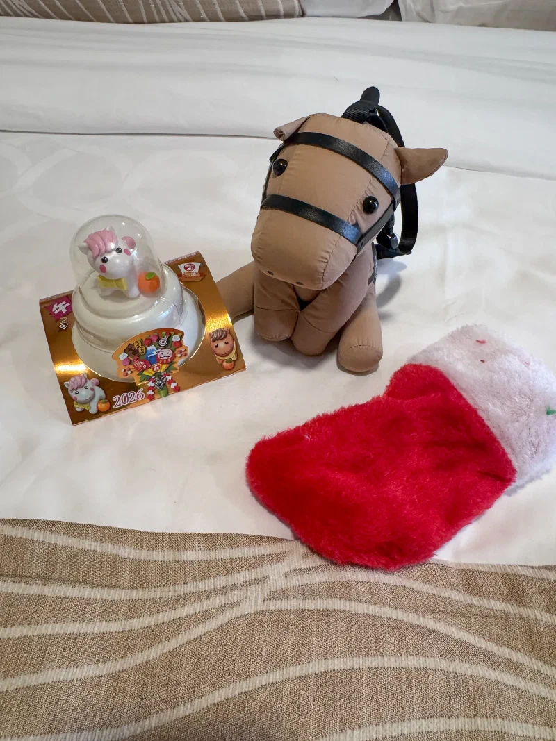 Chestnut the horse plush next to a small horse figurine under a dome with a Japanese card