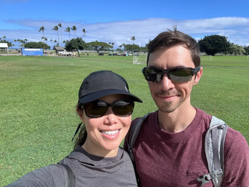 Nicholas and Pokin selfie at a park in Hilo with palm trees and green field