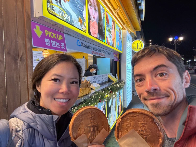 Nicholas and Pokin holding hwangnam-ppang street food at night