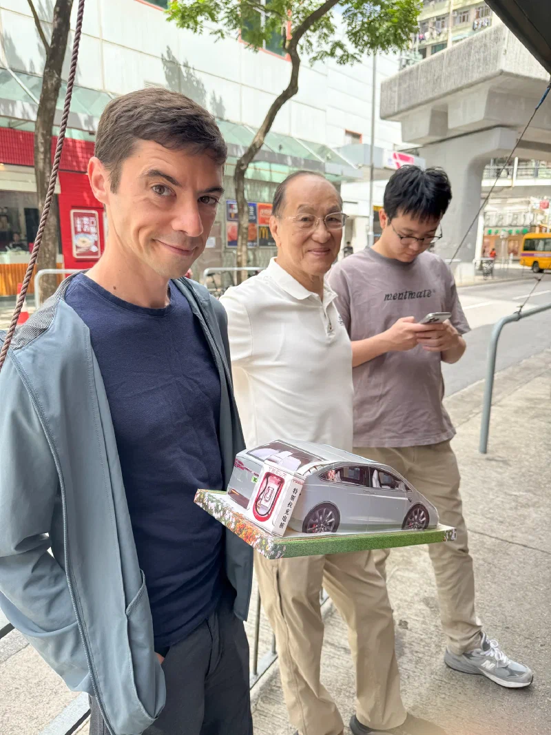 Nicholas holding a paper Tesla with a paper Supercharger
