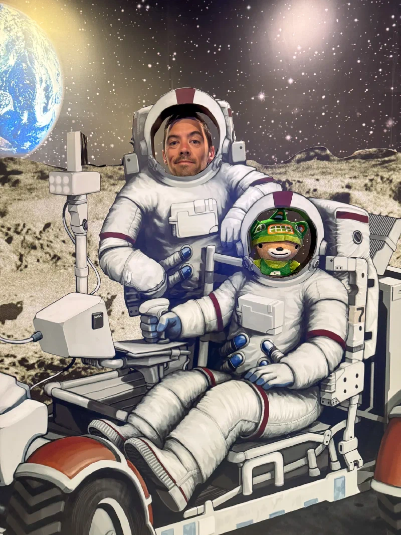 Sumi and Nicholas posing as astronauts in a lunar rover cutout at the planetarium