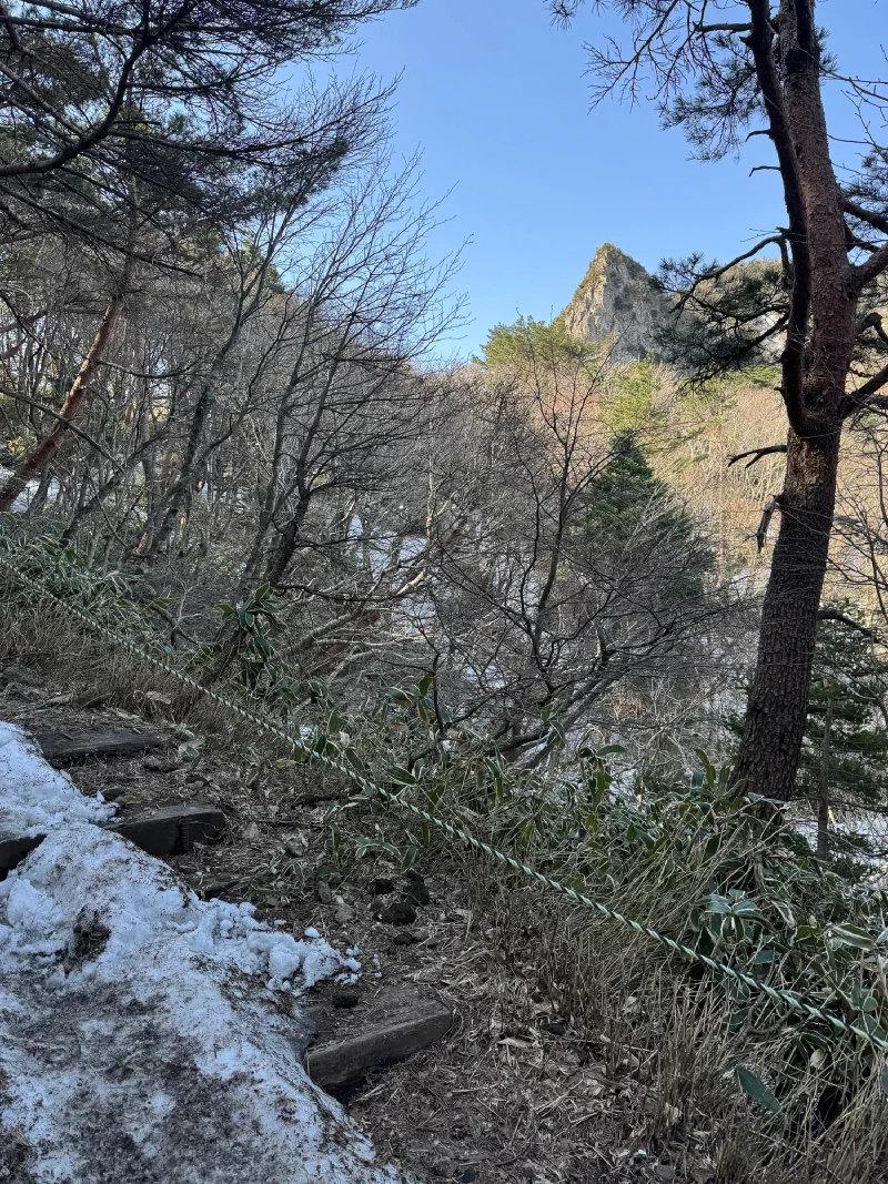 Snowy trail with volcanic rock spire visible through the trees