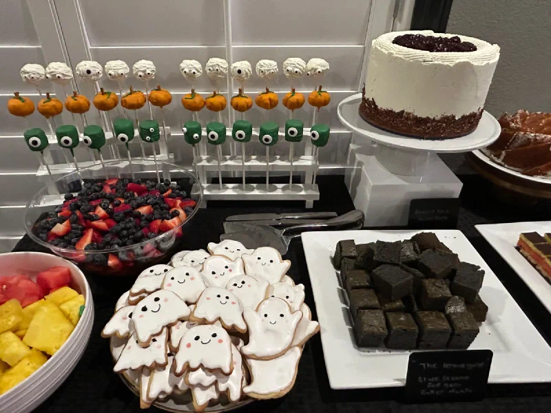 Halloween dessert table with cake pops, ghost cookies, brownies, and cakes