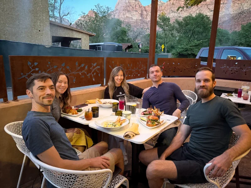 Group dinner at an outdoor restaurant with Zion cliffs behind