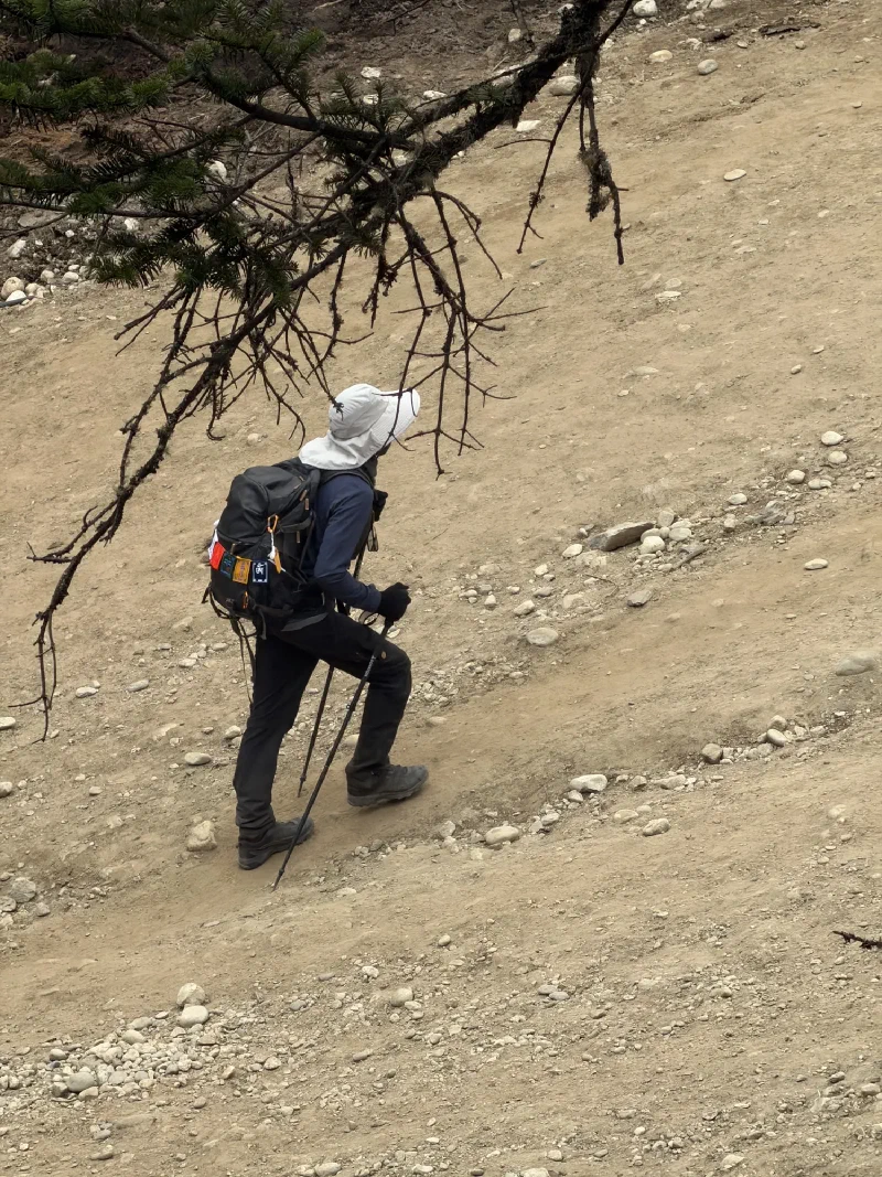 Nicholas climbing a steep trail with trekking poles and a full pack