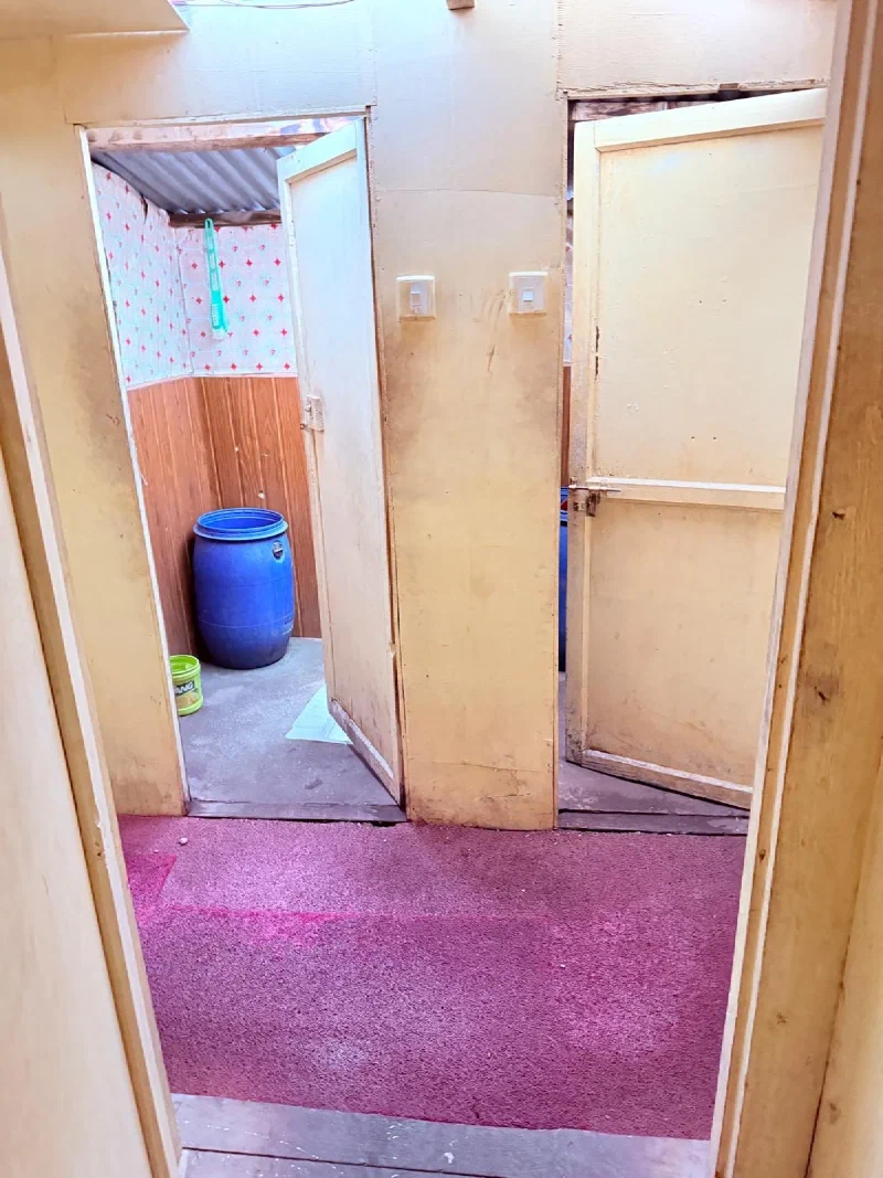 Lodge hallway showing shared bathroom with blue water barrel