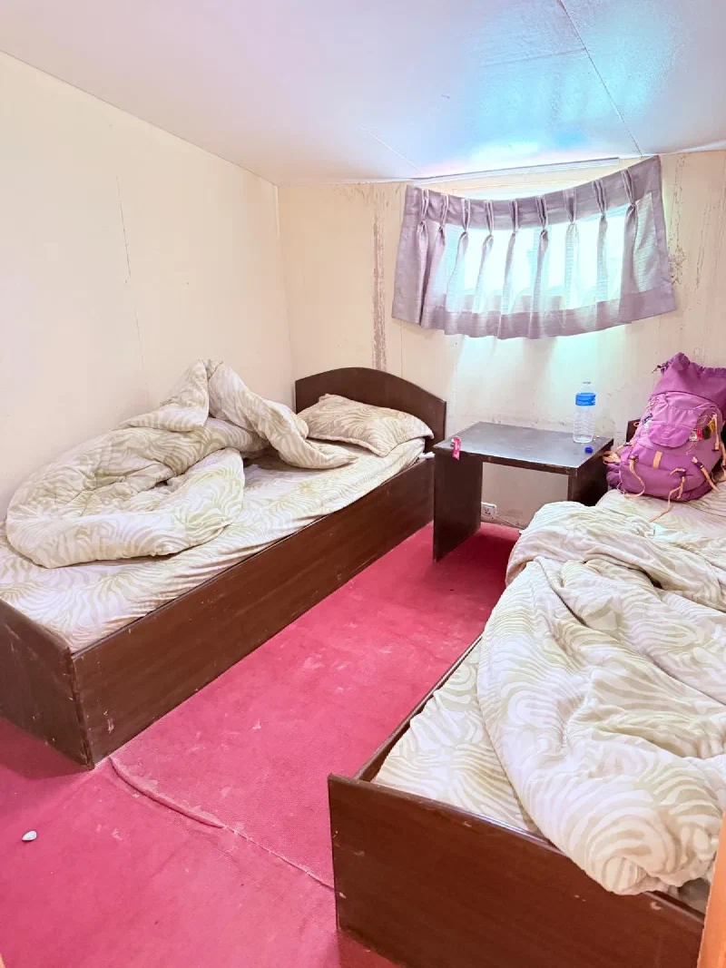 Thukla lodge room with two beds and a purple backpack