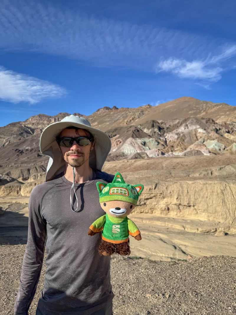 Nicholas holding Sumi Bear in front of Artist's Palette colorful hills in Death Valley