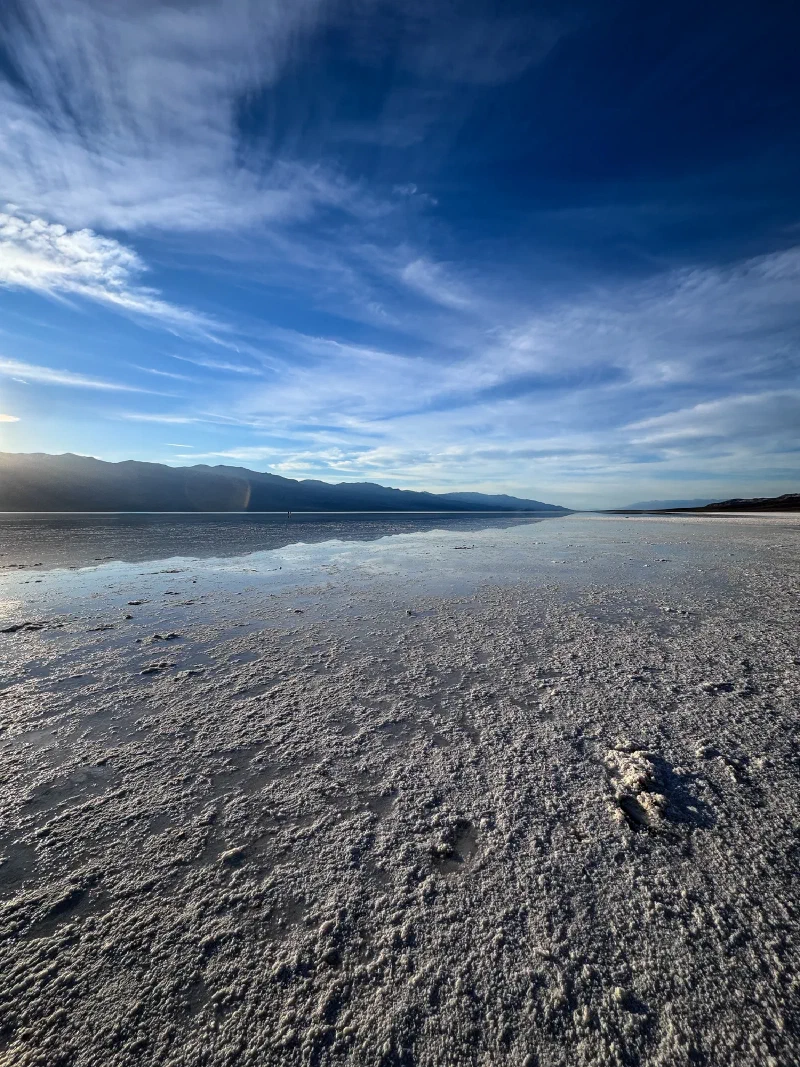 Badwater Basin salt flats with standing water reflecting the sky and mountains