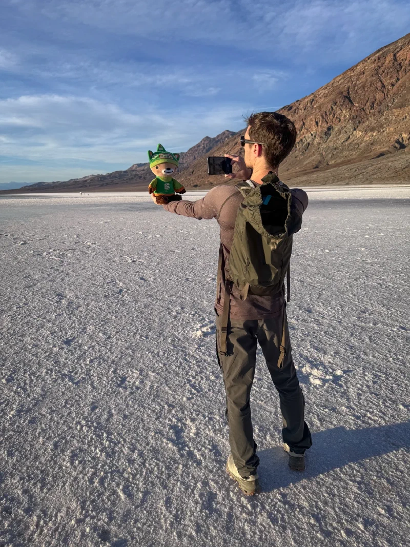 Nicholas holding Sumi Bear out on the salt flats taking a photo