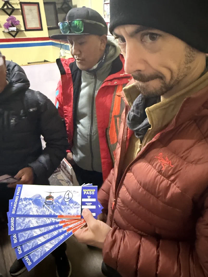 Nicholas indoors holding several helicopter boarding passes, looking skeptical