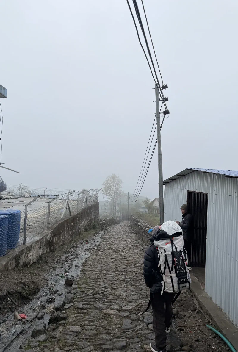 A guide leading the group down a foggy rocky path past the airport fence