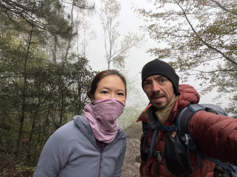 Nicholas and Pokin on a foggy forest trail, Pokin wearing a pink mask
