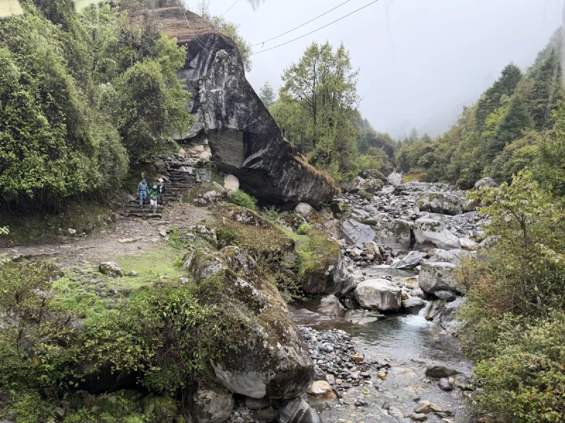 A rocky trail beside a stream under heavy gray sky