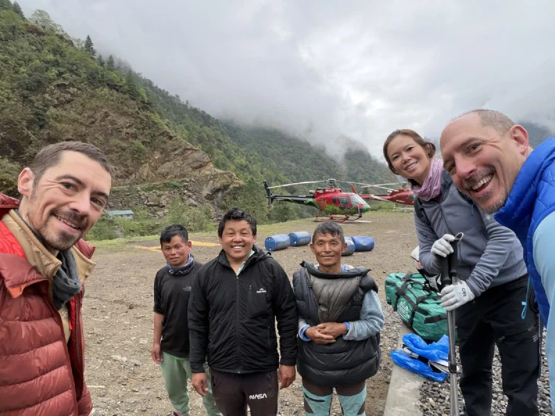 The group with porters near parked helicopters in heavy cloud