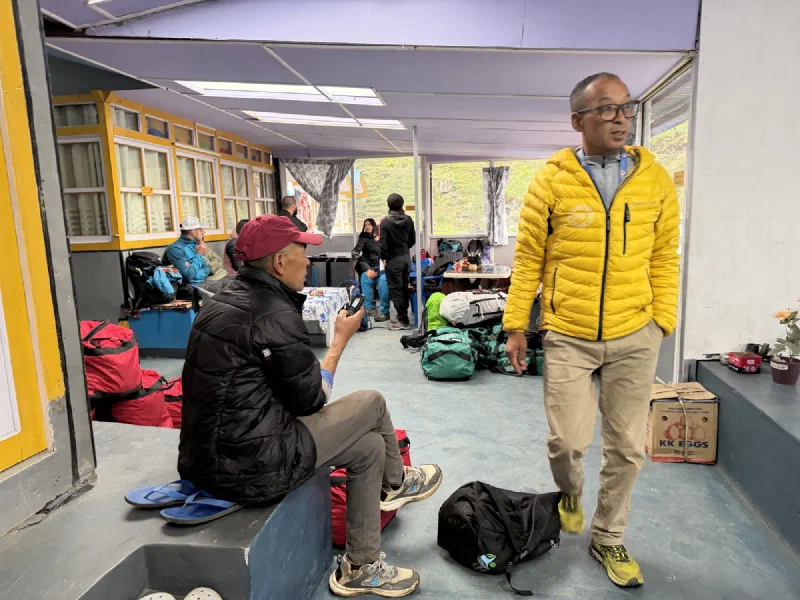 The Sherpa who runs the terminal, in a yellow jacket, inside the rustic airport waiting room
