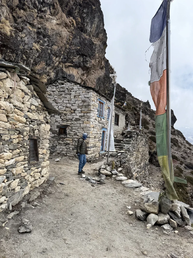 Stone buildings with prayer flags against rock wall