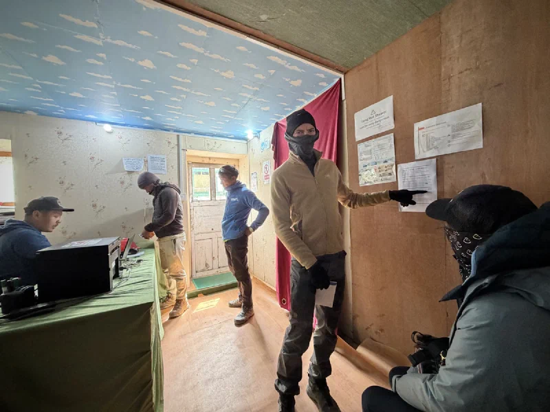 Nicholas pointing at the price board inside the Mountain Medical Institute