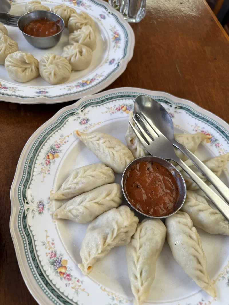 Two plates of momos with red chutney dipping sauce